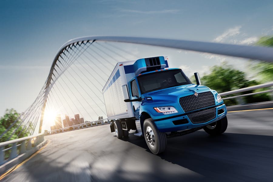 A blue truck driving on a bridge