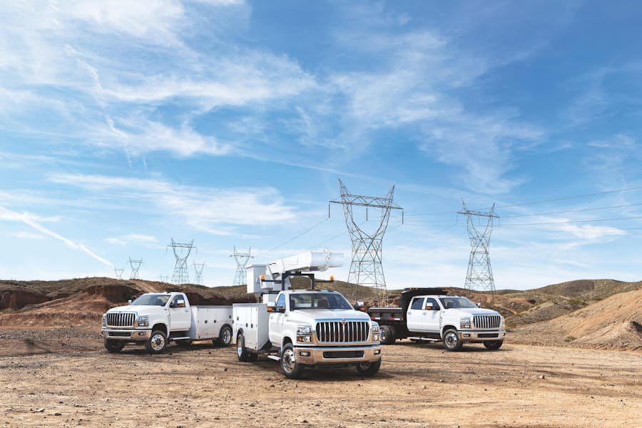 A group of white trucks parked in a dirt area