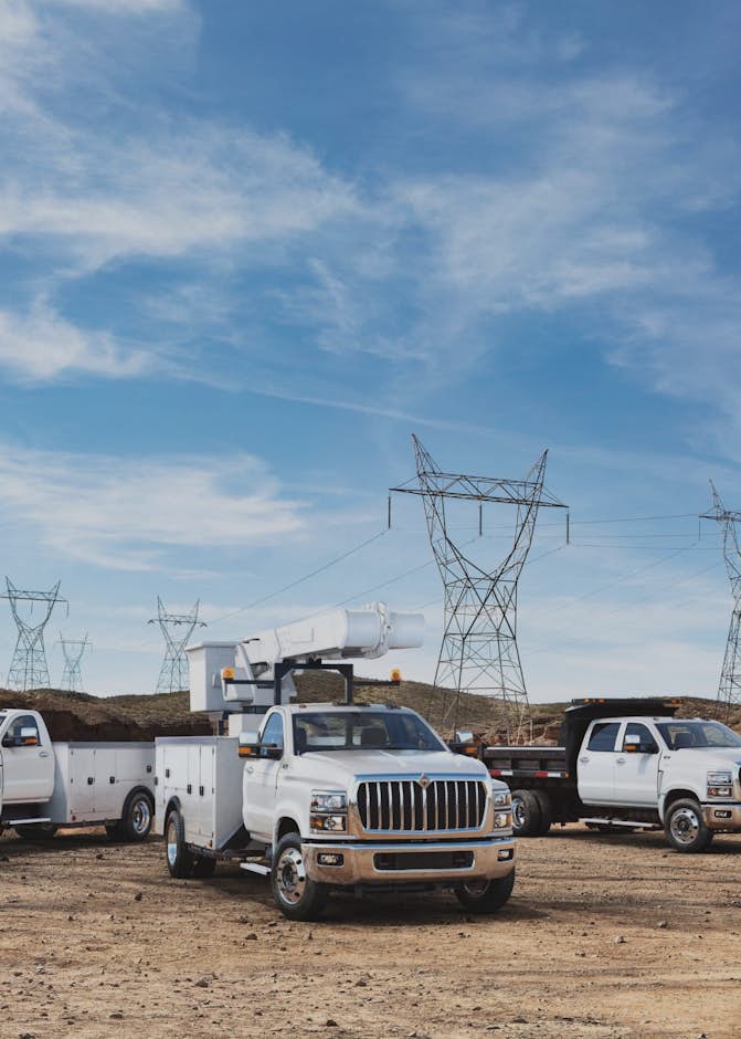 A group of white trucks parked in a dirt area