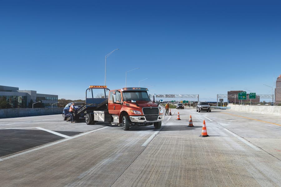 A tow truck with a tow truck on the side of the road