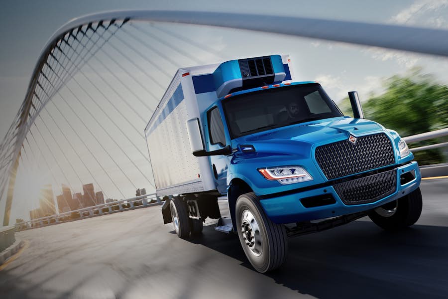 Blue truck driving on road under bridge