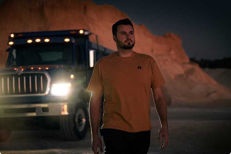 A person standing in front of a truck at dusk