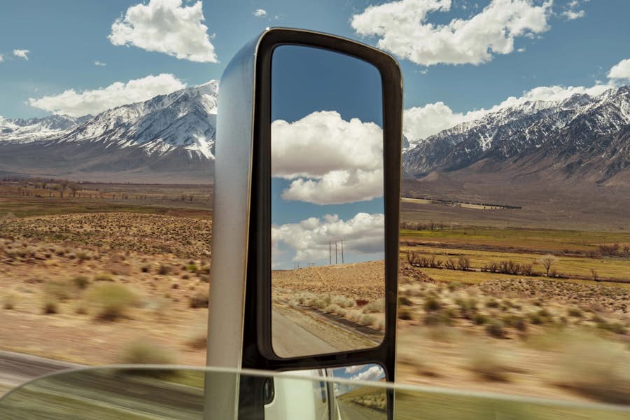 A mirror of a car with mountains in the background
