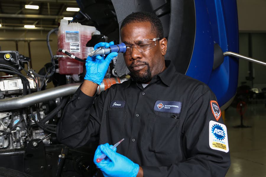 A person wearing gloves holding a tool to his eye