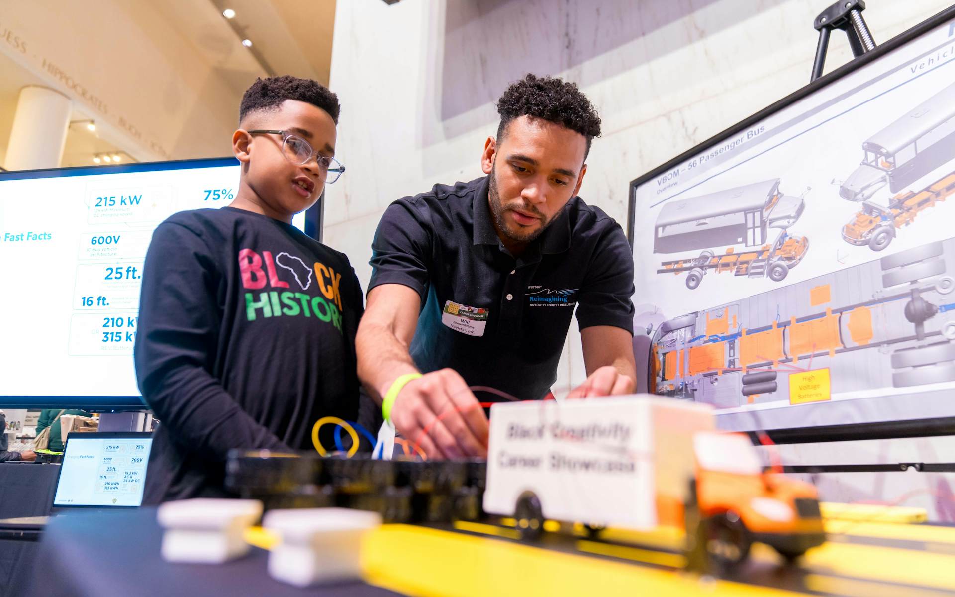A child and an adult looking at a miniature truck.